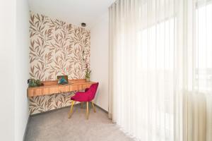 Habitación con escritorio y silla roja. en Medirooms Apartments, en Feldkirchen bei Graz