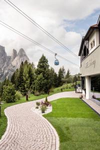 un camino empedrado frente a un edificio con remonte en Hotel Schmung, en Alpe di Siusi