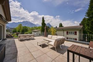 patio z kanapą, stołami i górami w obiekcie Terrace Vista Interlaken w mieście Interlaken