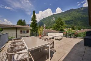 patio z białym stołem i krzesłami oraz górami w obiekcie Terrace Vista Interlaken w mieście Interlaken