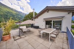 patio ze stołem, krzesłami i parasolem w obiekcie Terrace Vista Interlaken w mieście Interlaken