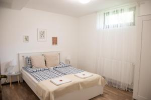 a white bedroom with a bed with two towels on it at Csillagvirág Apartman Gyula in Gyula