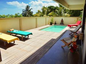 a patio with a pool and a table and chairs at Happy Days Guest House in Le Morne