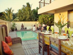 a patio with a table and chairs next to a swimming pool at Happy Days Guest House in Le Morne