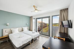 Habitación de hotel con cama y balcón en All Suites La Teste – Bassin d’Arcachon, en La Teste-de-Buch