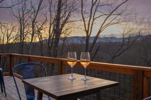 twee glazen wijn zittend op een houten tafel op een balkon bij Mountain Retreat Game Room, BBQ, & Scenic Views in Sevierville