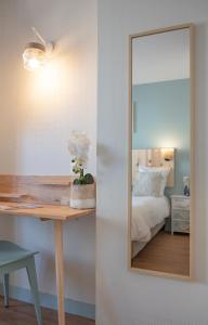 - une chambre avec un miroir et un bureau avec un lit dans l'établissement Hôtel Le Rivage vue sur mer - Châtelaillon-plage, à Châtelaillon-Plage