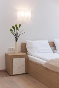 ein Schlafzimmer mit einem Bett und eine Vase mit Blumen auf einem Nachttisch in der Unterkunft Katrin Apartments in Jūrmala