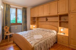 sypialnia z dużym łóżkiem i drewnianymi szafkami w obiekcie Cozy apartment near Cortina w mieście San Vito di Cadore