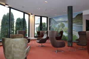 a waiting room with chairs and a wall of windows at EINSTEIN Hotel am Römerpark in Andernach