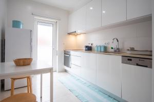 une cuisine avec des placards blancs et une table dans l'établissement Iris Apartment, à Nazaré