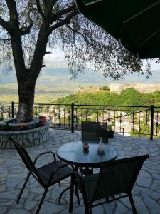 een patio met een tafel en stoelen en een boom bij Panoramic Vlachos in Gjirokastër