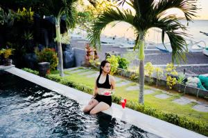 Una donna in bikini seduta in piscina di Alam Bali Beach Resort ad Amed