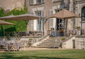 a patio with tables and umbrellas in front of a building at Château De Pray in Amboise