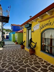 a yellow building with potted plants on a street at Alkionisnest in Arkoudi