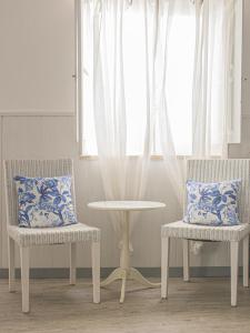 two chairs and a table in a room with a window at Vinnus Guesthouse in Ericeira