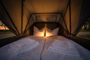 a bed in a tent with white sheets and pillows at Marina Martinshafen - Beach life in Sassnitz