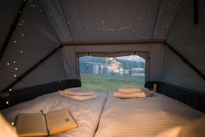 a bed in a tent with a book and a window at Marina Martinshafen - Beach life in Sassnitz