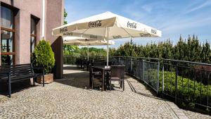 une table et des chaises sous un parasol à côté d'une clôture dans l'établissement Hotel Esperanto, à Świdnica