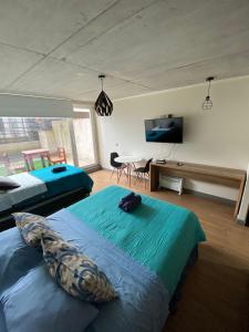 een slaapkamer met 2 bedden en een televisie en een tafel bij Depto ESTUDIO CON TERRAZA EN EDIFICIO BARCELONA in Temuco