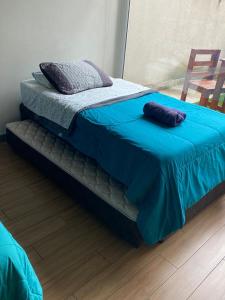 een bed met een blauwe deken erop bij Depto ESTUDIO CON TERRAZA EN EDIFICIO BARCELONA in Temuco