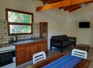 uma cozinha com um fogão, uma mesa e cadeiras em Las Casitas de Piedra I em Villa General Belgrano