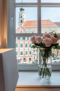 a vase filled with pink roses sitting on a window sill at Hotel Forstinger - Boutique Hotel Schärding in Schärding