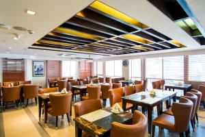 een restaurant met tafels, stoelen en ramen bij Platinum Grand in Dhaka