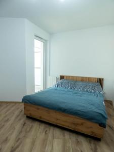 een bed in een witte kamer met een houten vloer bij Apartament Flat 33 Suwałki in Suwałki