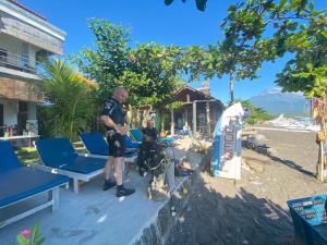 Un uomo in piedi su una spiaggia con una tavola da surf di Tudes Homestay ad Amed