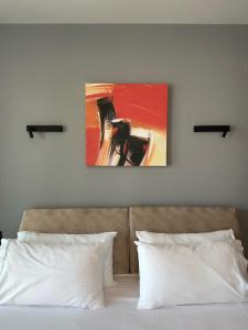 uma cama com duas almofadas e um quadro na parede em The Victoria Lefkada em Lefkada Town