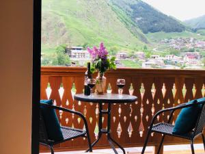 - une table avec deux verres de vin sur le balcon dans l'établissement Fiten house, à Kazbegi