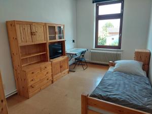 a bedroom with a bed and a cabinet and a television at Monteurzimmer bei der Gärtnerei in Grünendeich