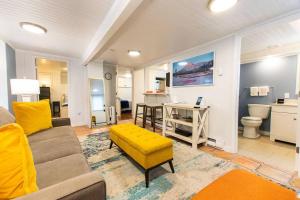 a living room with a couch and a yellow stool at Condo with Wading Pool Dog Welcome in Provincetown