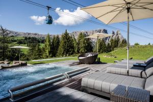 una piscina con sillas y sombrilla en Hotel Schmung, en Alpe di Siusi