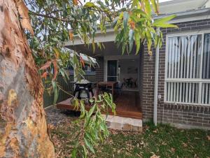 eine Veranda eines Hauses mit einer Holzterrasse in der Unterkunft Bateau Bay Retreat in Bateau Bay