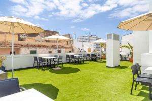 un toit-terrasse avec pelouse, tables et parasols dans l'établissement Sholeo Lodges La Cícer Flats, à Las Palmas de Gran Canaria