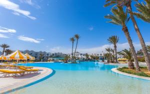 uma grande piscina com palmeiras e cadeiras em Djerba Holiday Beach em Midoun