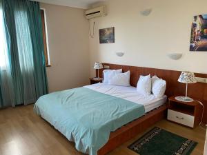 a bedroom with a large bed with a blue blanket at Guest House Golden Flake 4km from Bolata beach in Bŭlgarevo