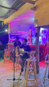 a man playing a guitar in a bar at Achita Cottages in Senaru