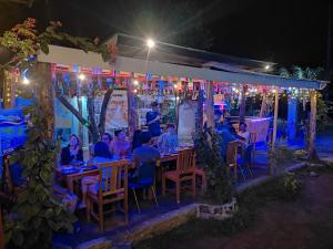 a group of people sitting at tables at night at Achita Cottages in Senaru