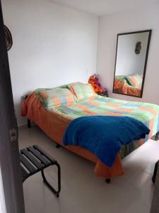 a bedroom with a bed and a mirror and a chair at Apartamento hogareño in Pereira