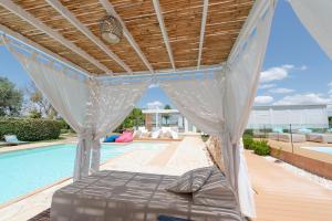 ein Bett unter einer Pergola neben einem Pool in der Unterkunft Le Grancìe in Porto Cesareo