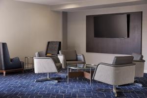 Courtyard by Marriott St. Louis Downtown West في سانت لويس: غرفة انتظار مع كراسي وتلفزيون بشاشة مسطحة