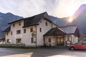 un bâtiment avec une voiture rouge garée devant lui dans l'établissement Dormio Gasthof Höllwirt, à Obertraun