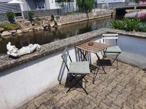 une table et deux chaises assises à côté d'une rivière dans l'établissement Moments Apartment, à Rust