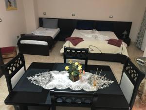 a room with two beds and a table with flowers on it at Maison Centre in Shkodër