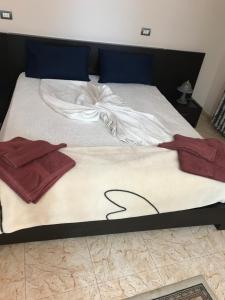 a bed with white sheets and red towels on it at Maison Centre in Shkodër