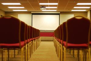 ein leeres Klassenzimmer mit roten Stühlen und einem weißen Bildschirm in der Unterkunft Ramada by Wyndham Bettendorf in Bettendorf