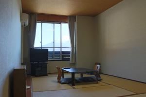 uma sala de estar com uma mesa e uma televisão em Shoji Mount Hotel em Fujikawaguchiko